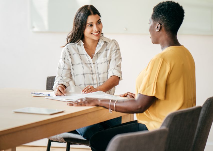 a landlord in a yellow sweater screening a tenant and going over rental documents