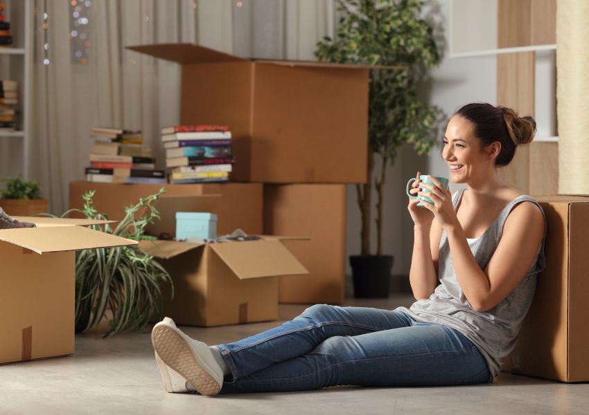 new tenant sipping coffee on the floor surrounded by moving boxes